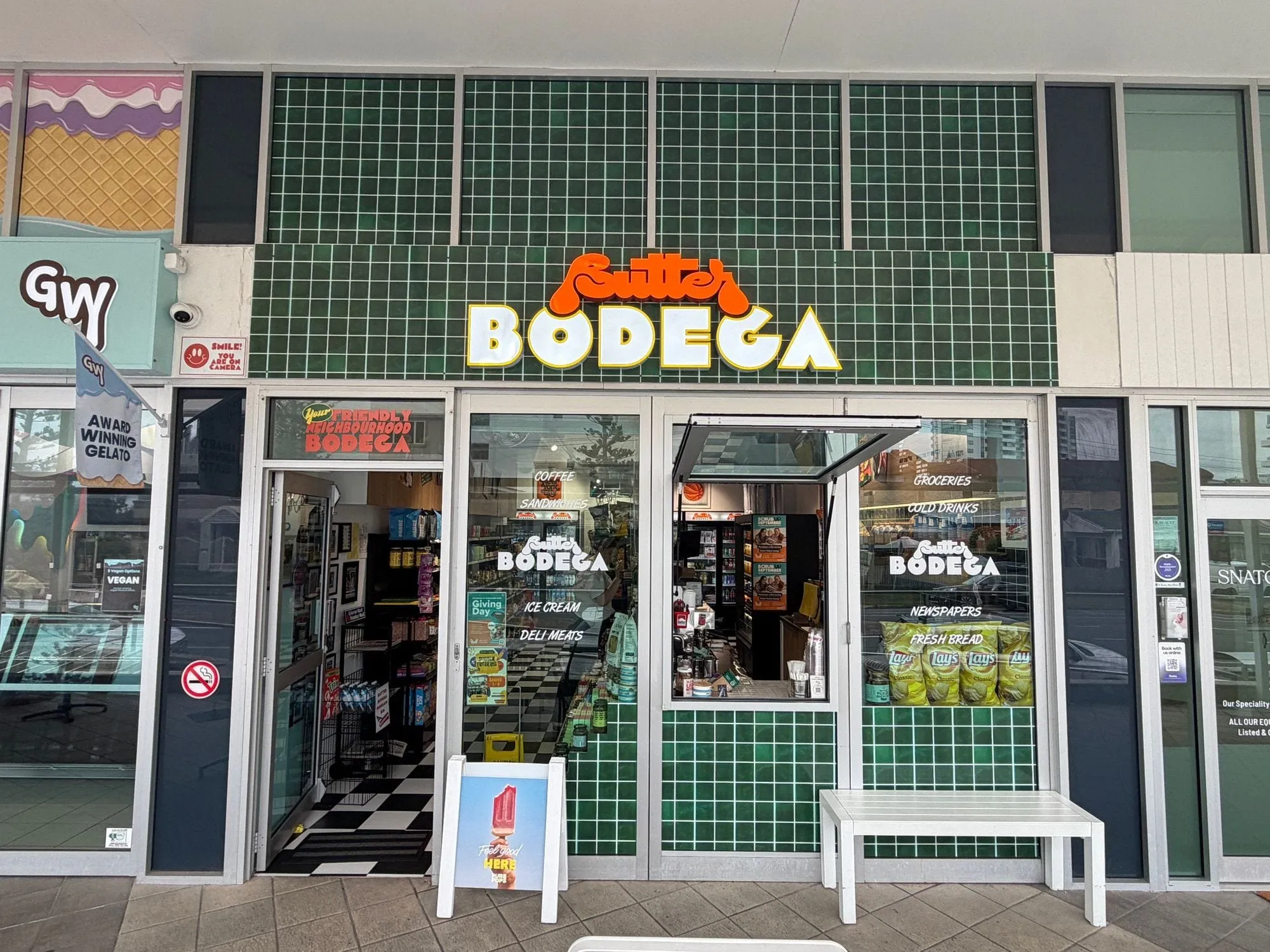The Butter Bodega shopfront at Aqua, a dark green tiled frontage with the yellow BODEGA sign above the window.