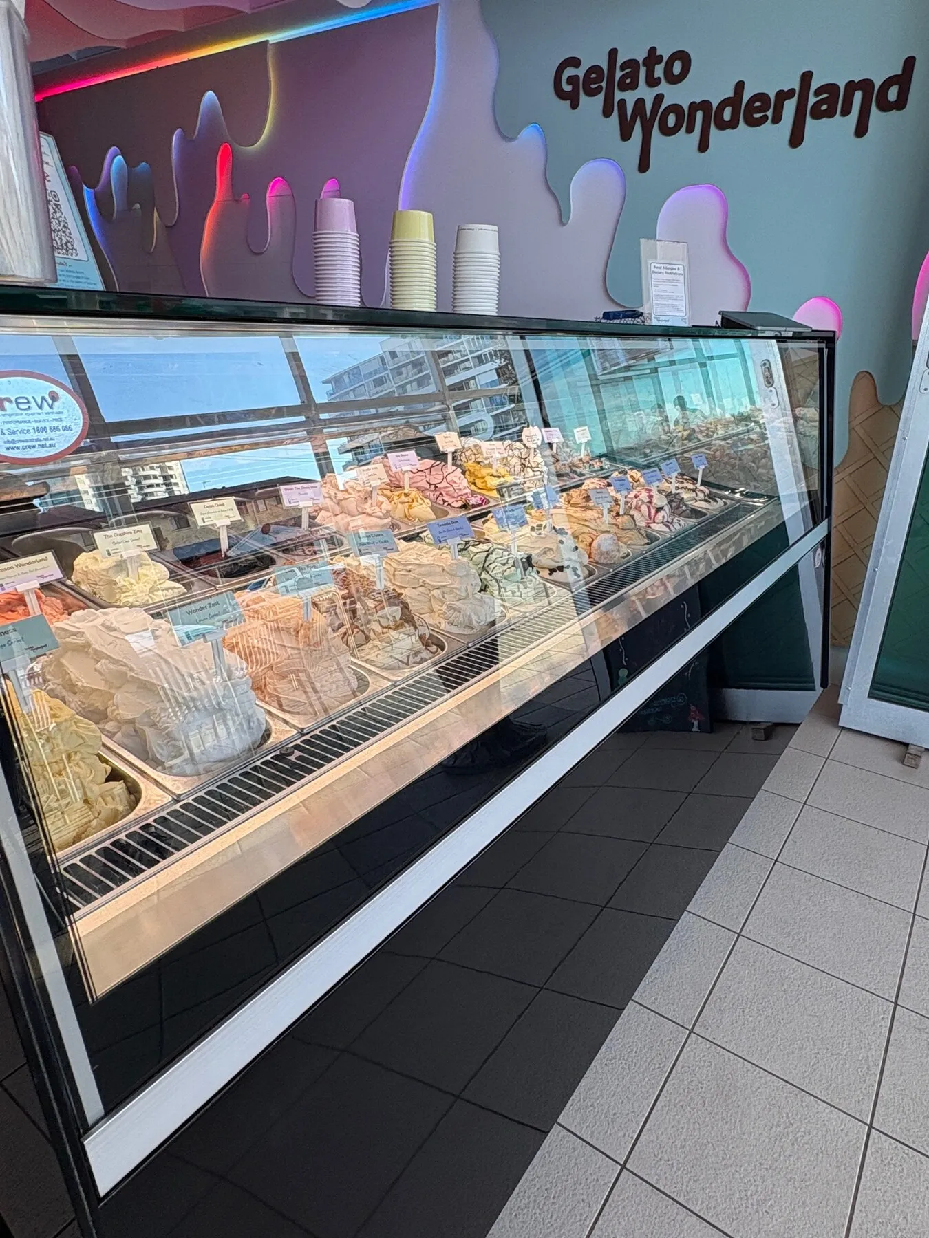 The Gelato Wonderland cabinet filled with colourful flavours under the glowing wave ceiling.
